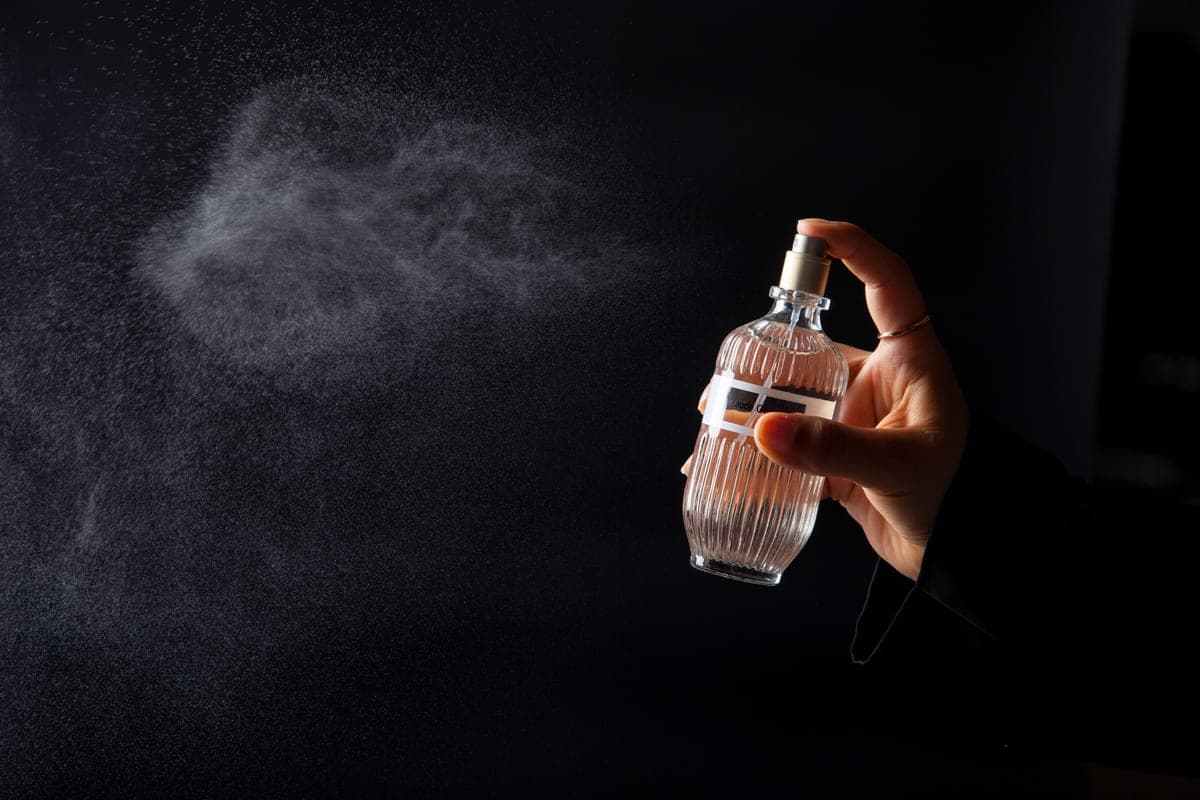 A fine mist of fragrance caught in low light against a dark background