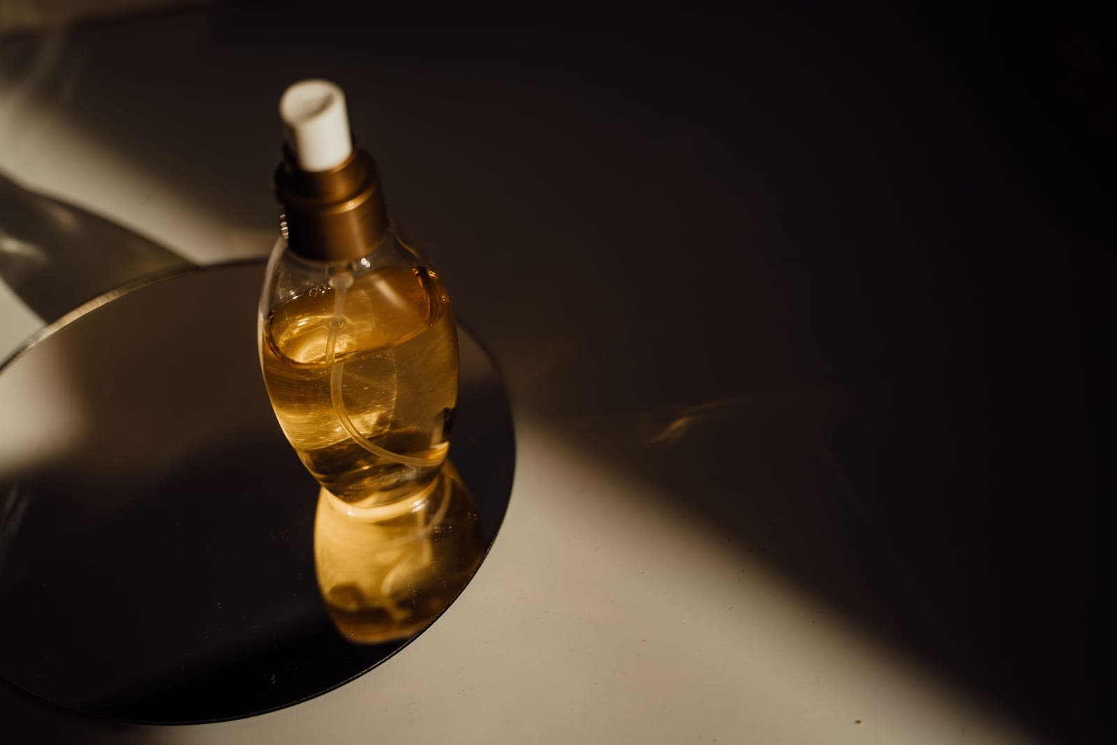 Amber glass fragrance and serum bottles arranged in low, warm light