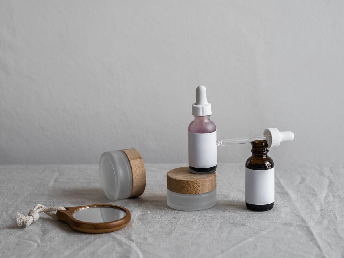 Two glass cosmetic bottles side by side on a dark surface