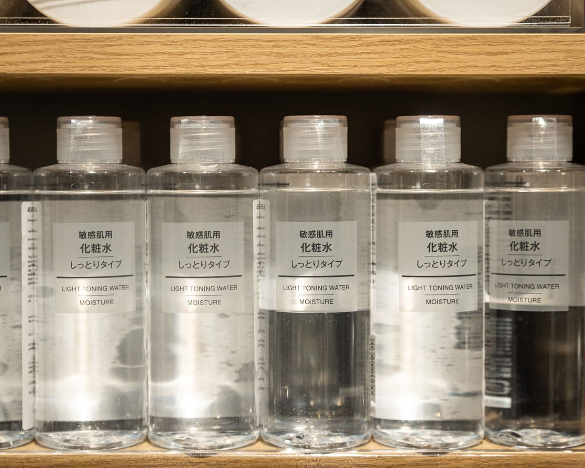 Skincare bottles arranged along a dark shelf in low light